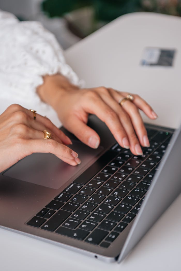 The Art of Drawing Readers In: Your attractive post title goes here Hands of a woman typing on a laptop keyboard indoors, showcasing rings and fashion.